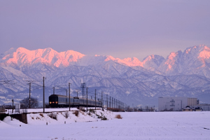 夕陽に輝く立山連峰とトワイライトエキスプレス